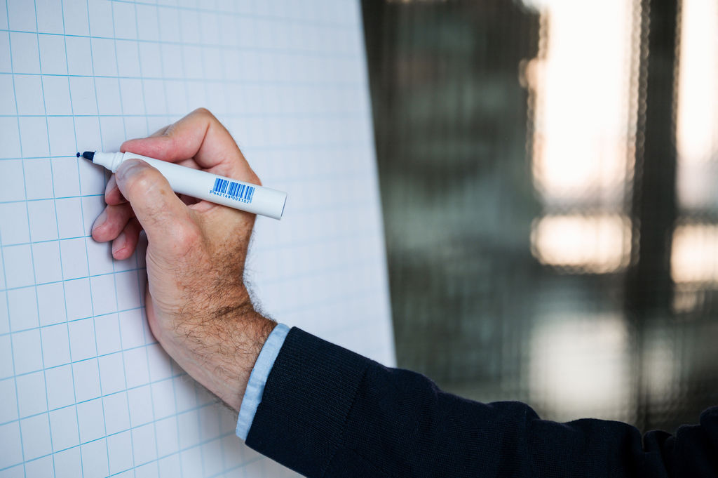 Eine Hand schreibt mit einem Stift auf kariertem Papier.